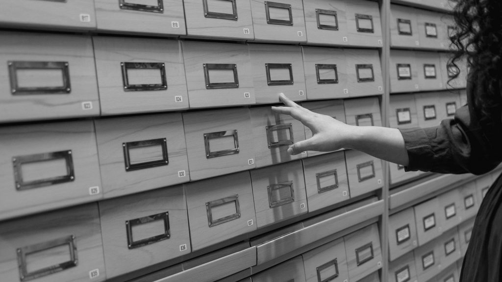 A Person Standing Near Data Base Wooden Drawer