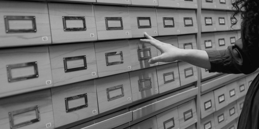 A Person Standing Near Data Base Wooden Drawer